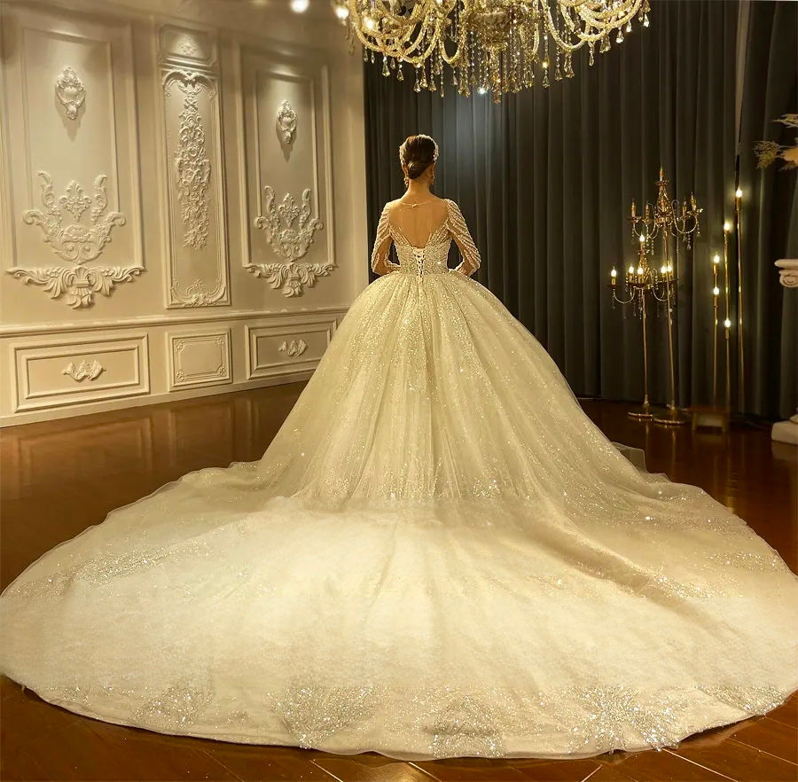 Dramatic rear view of a royal wedding dress emphasizing the expansive, glittering cathedral-length train spread across a boutique showroom floor.