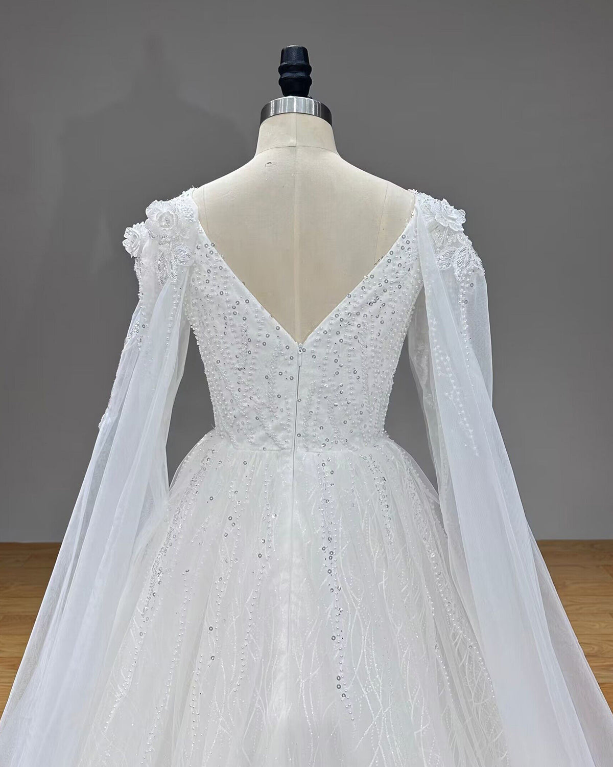 Symmetrical back close-up of a modern bridal bodice featuring a clean zipper closure and delicate pearl scatter patterns.