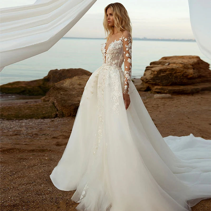 Bride wearing a convertible lace mermaid bridal gown with a detachable skirt, showcasing intricate floral embroidery and a romantic long-sleeve silhouette.