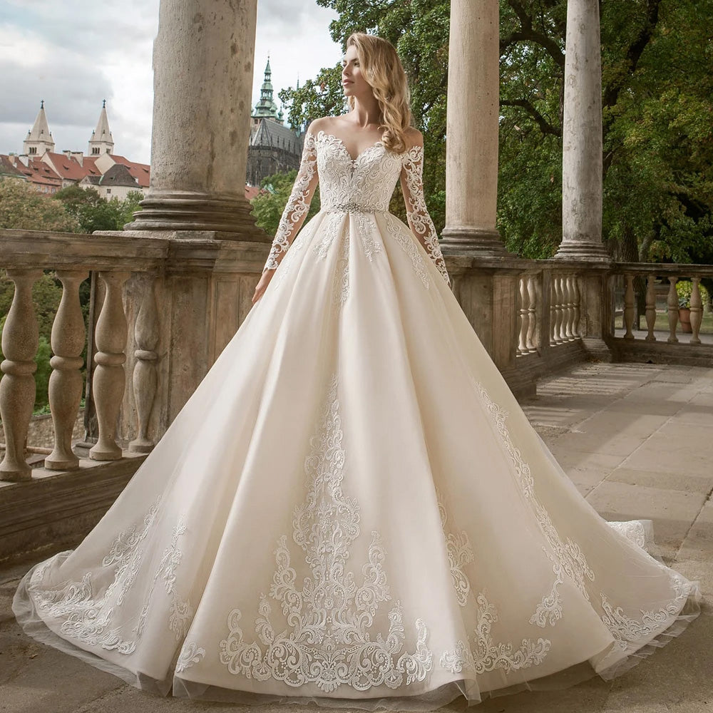 Elegant A-line wedding dress featuring long lace sleeves, an off-the-shoulder neckline, and a beaded waistline.