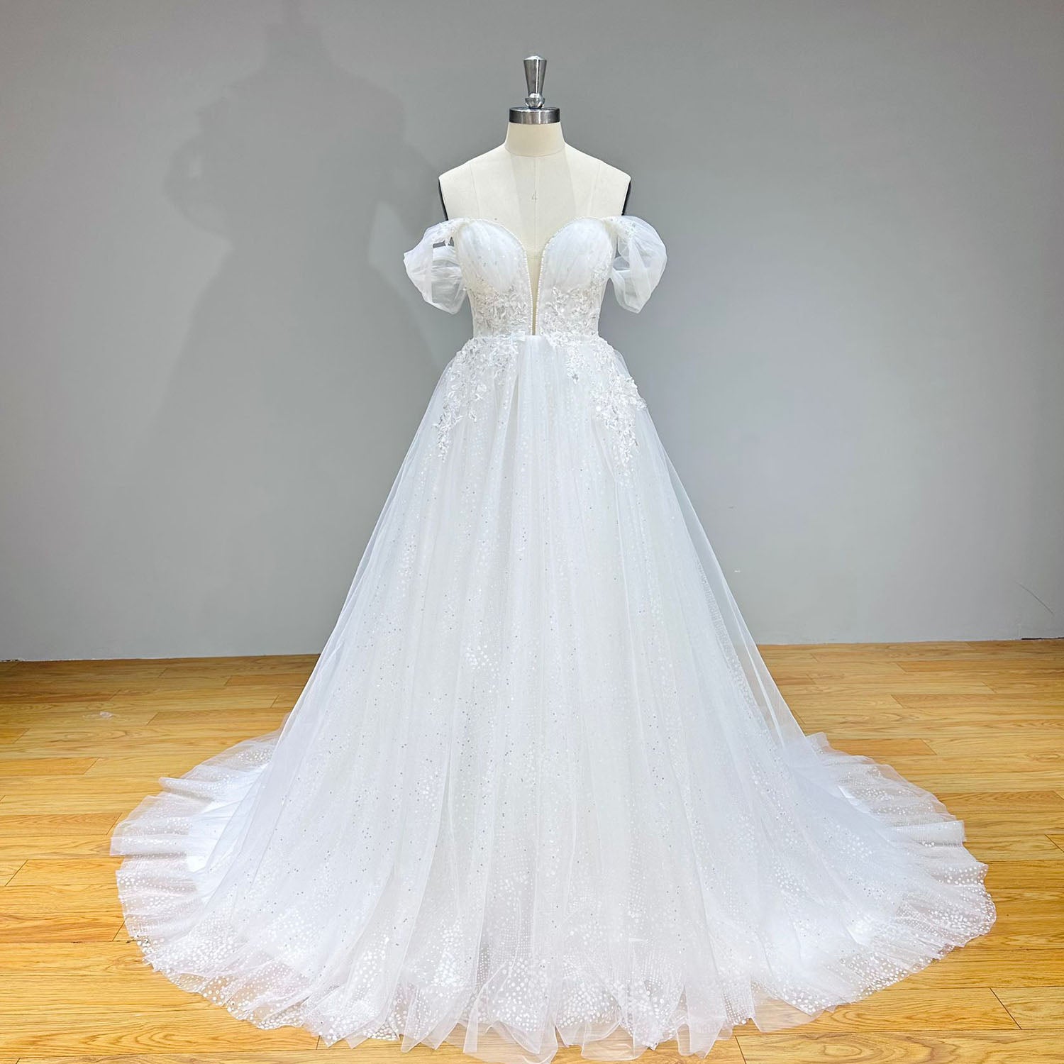 Three-quarter studio portrait of the complete off-shoulder beaded A-line wedding gown silhouette on a dress form, highlighting its premium multi-layered tulle construction.