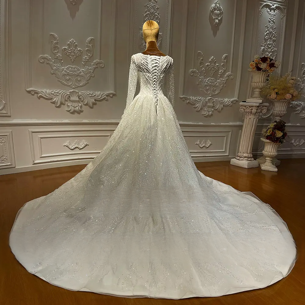 Back view of a luxury wedding dress on a mannequin, highlighting a traditional lace-up corset back and a dramatic, wide cathedral-length beaded train.