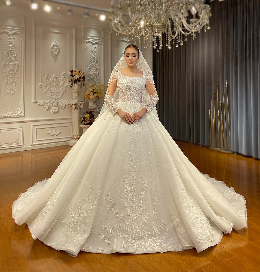 Front view of a shimmering pearl-adorned A-line wedding dress styled with a matching lace-trimmed bridal veil in a classic studio setting.