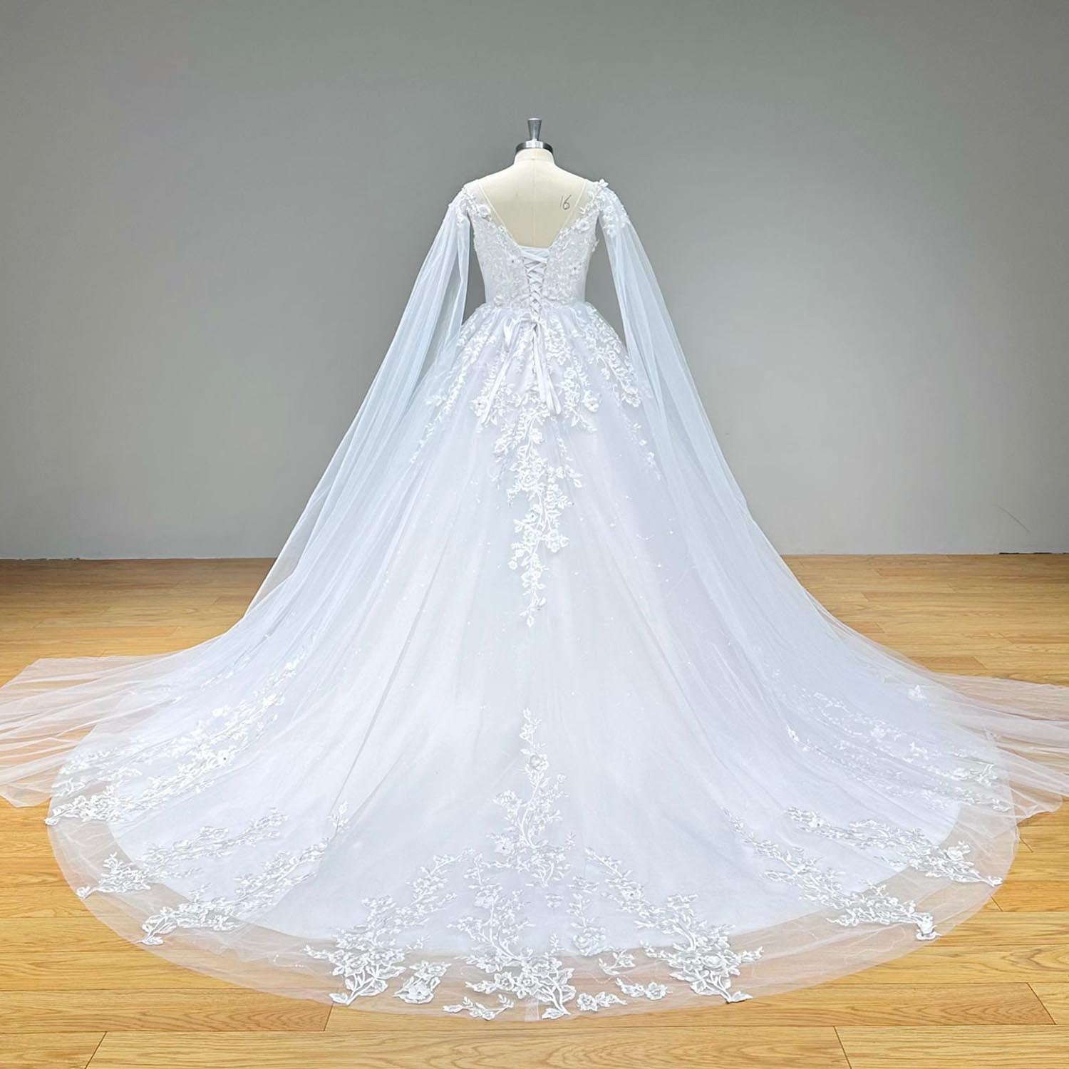 Dramatic full back view of an elegant backless ball gown wedding dress on a mannequin, displaying a classic corset lace-up back, a sweeping tulle train with vintage lace, and attached long sheer shawl sleeves.