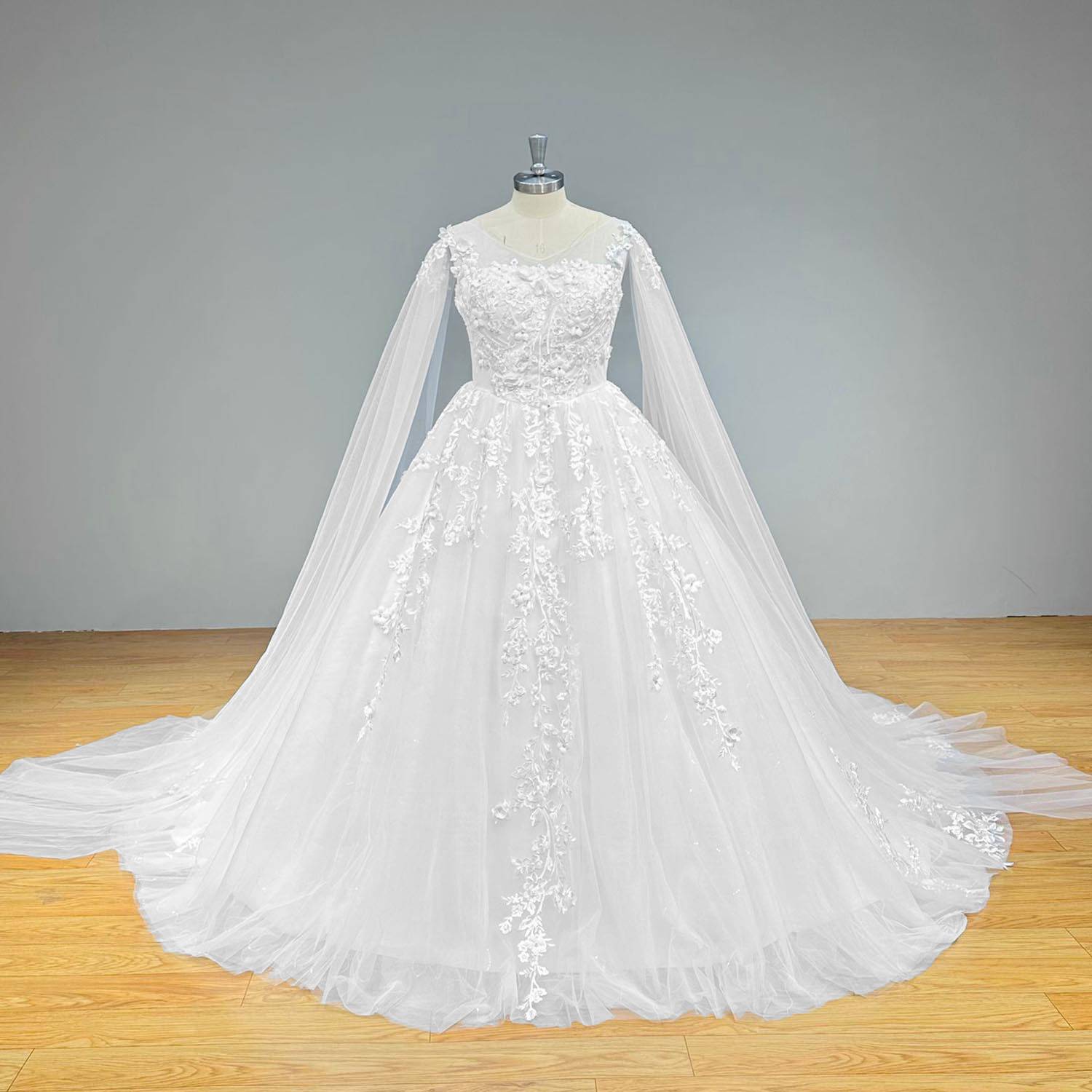 Wide front view of a vintage ball gown wedding dress on a mannequin, perfectly displaying the wide sparkling tulle skirt, intricate lace detailing, and elegant long shawl sleeves trailing to the floor.