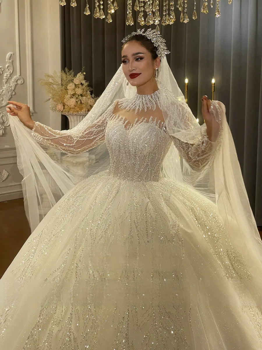 Close-up of a bridal gown's high-neck fringe collar and heavily beaded bodice, showcasing the handcrafted silver embroidery and long illusion sleeves.