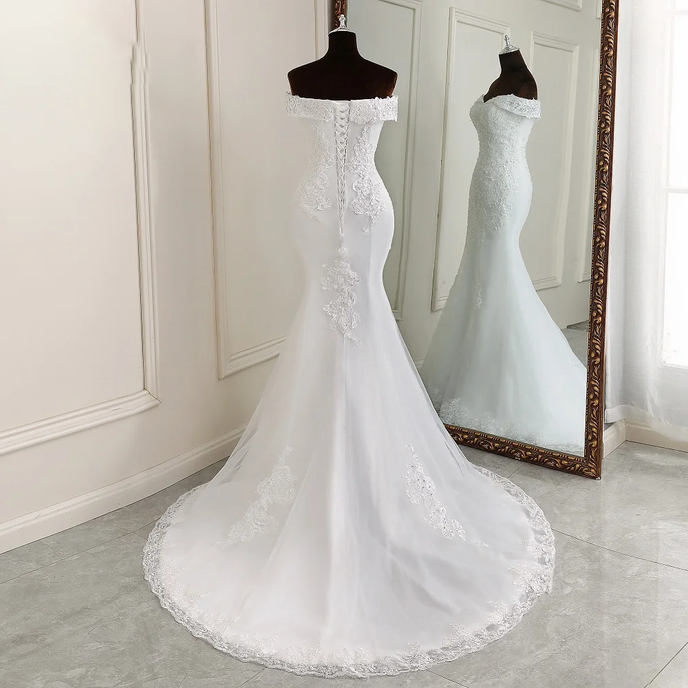 Studio portrait of an elegant boat neck mermaid bridal gown with delicate off-shoulder sleeves and a fitted silhouette.