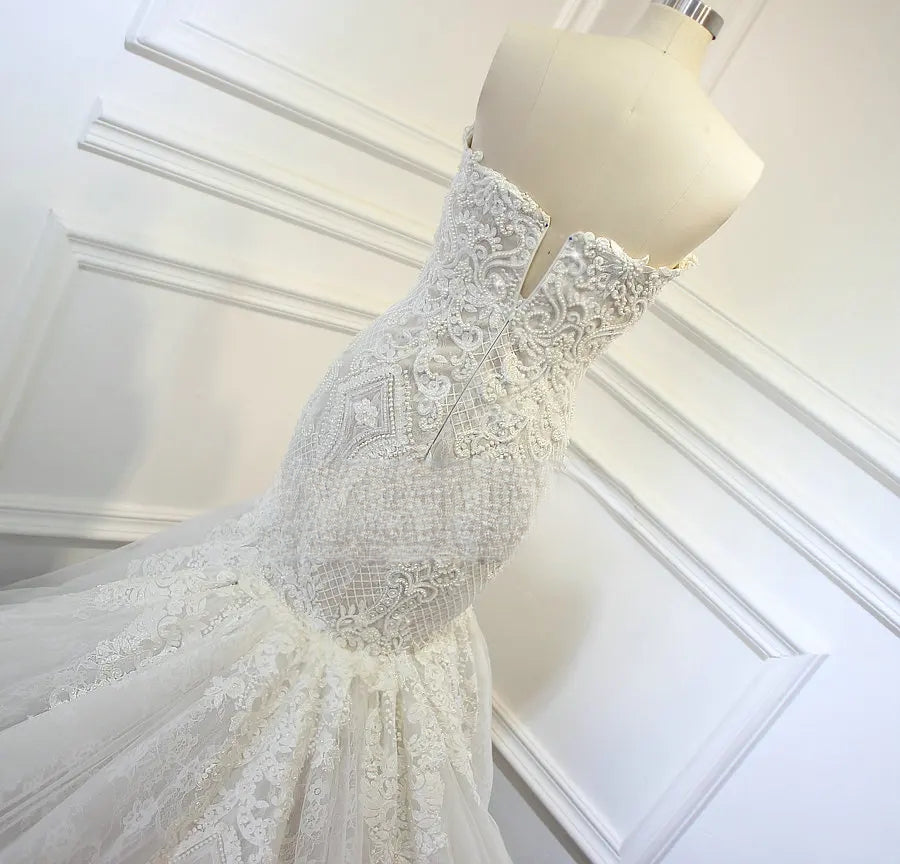 Close-up back detail of an elegant mermaid wedding dress, focusing on the intricate embroidery, fitted silhouette, and low-cut back design.