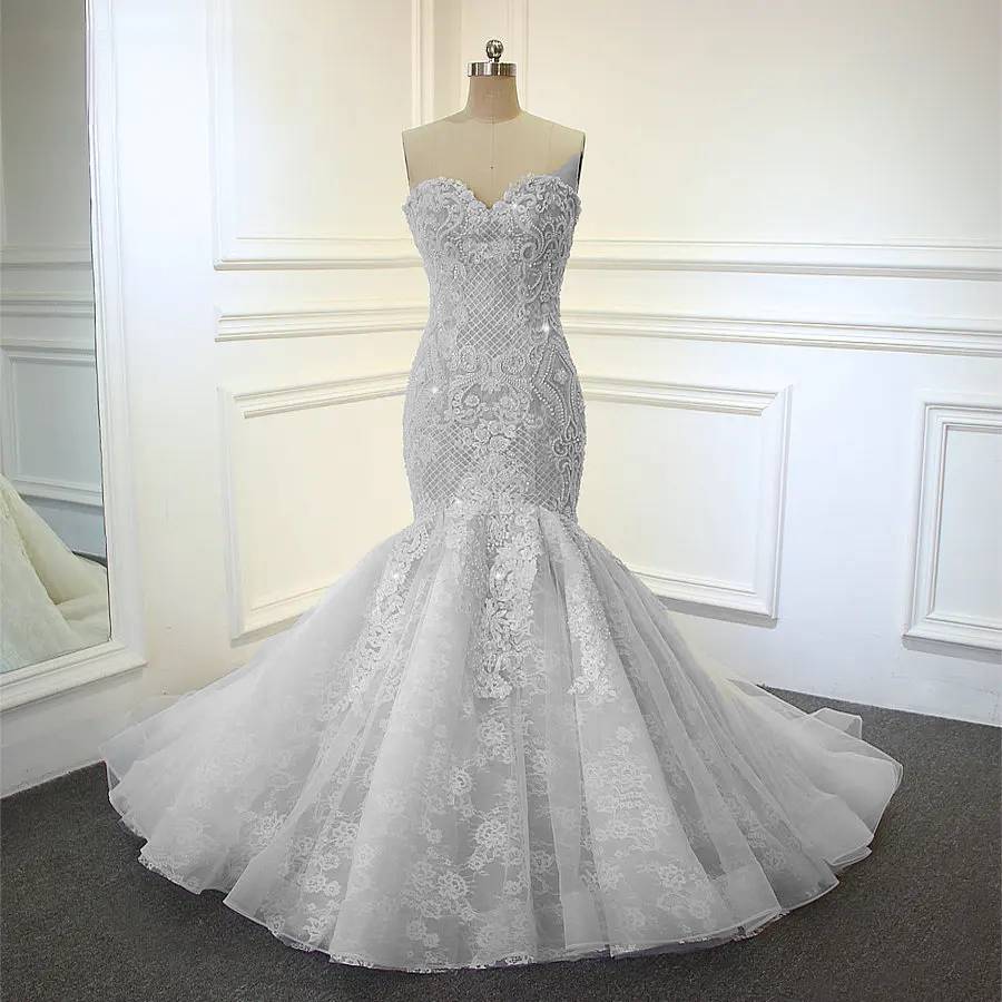 Front view of a luxury strapless mermaid bridal gown on a mannequin, showcasing detailed pearl and sequin embroidery over champagne lace.