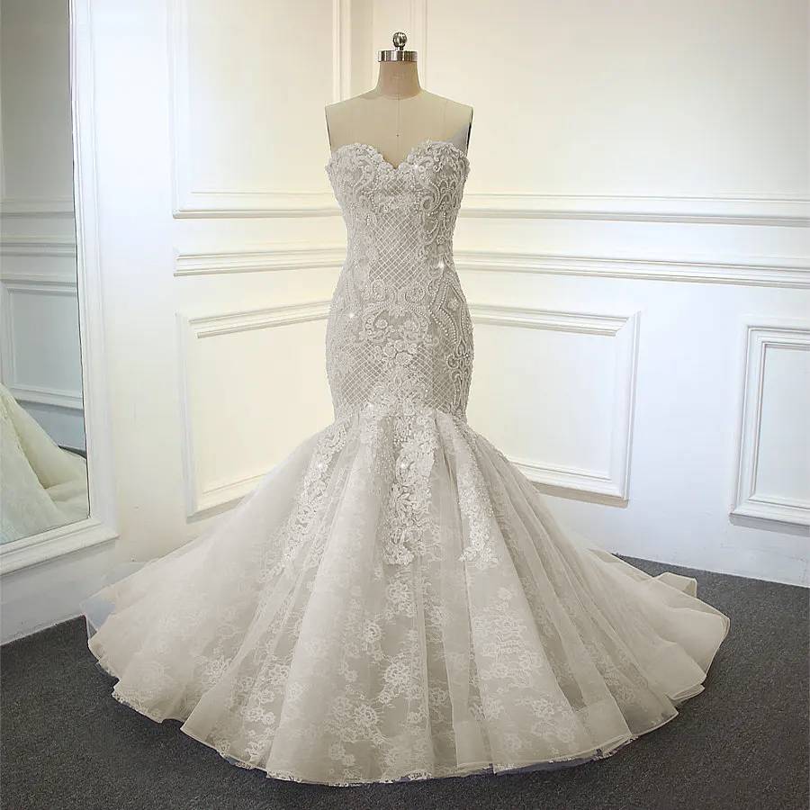 Mannequin display of an off-white beaded mermaid wedding gown featuring a structured bodice and voluminous flared lace hem.