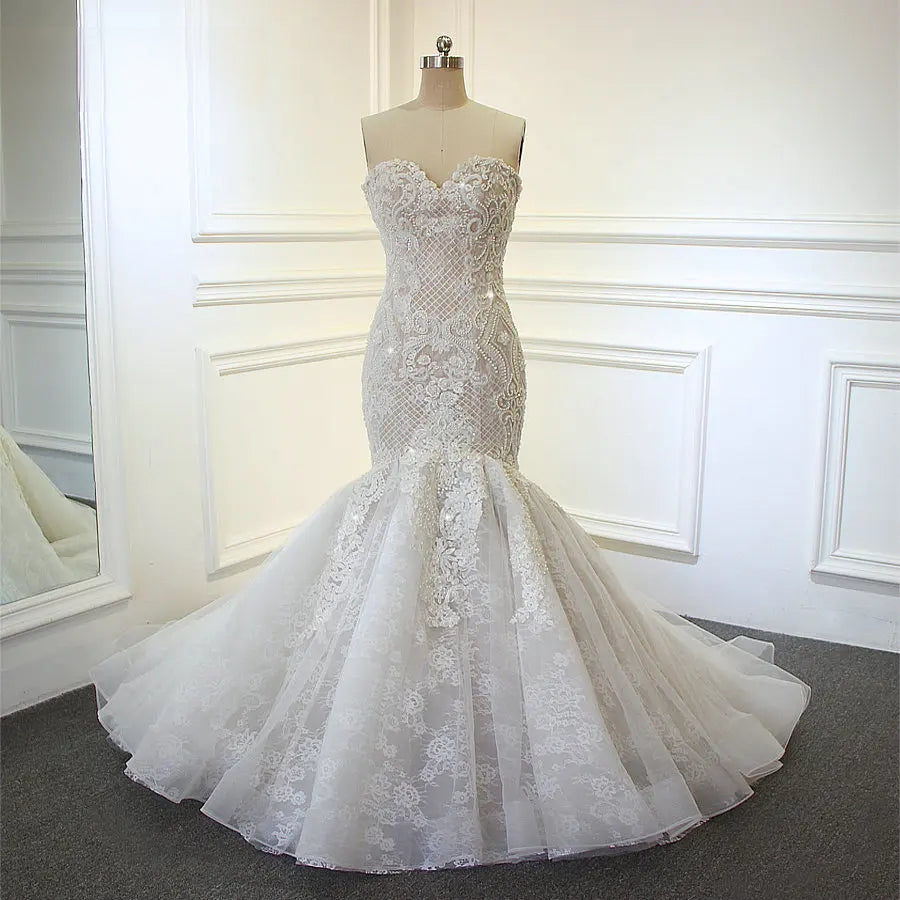 Front-facing shot of a designer mermaid bridal gown on a mannequin, emphasizing the intricate geometric lace patterns and luxury beadwork.