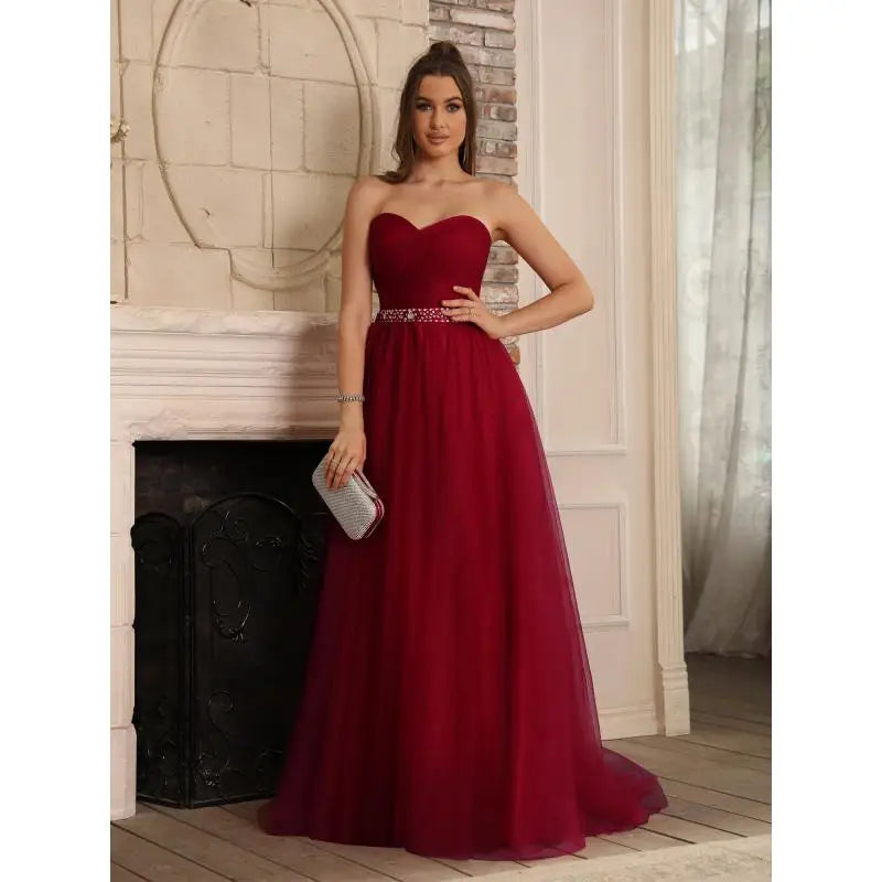 Elegant burgundy chiffon A-line formal dress featuring a sweetheart neckline and a shimmering crystal belt, styled with a silver clutch.