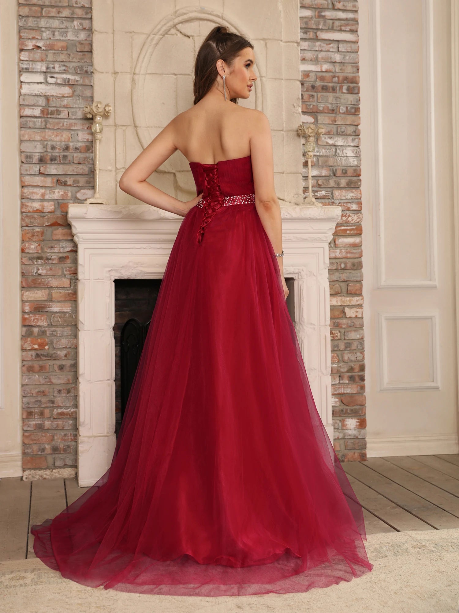Rear view of a burgundy A-line dress highlighting the adjustable lace-up corset back and crystal-beaded belt detail.