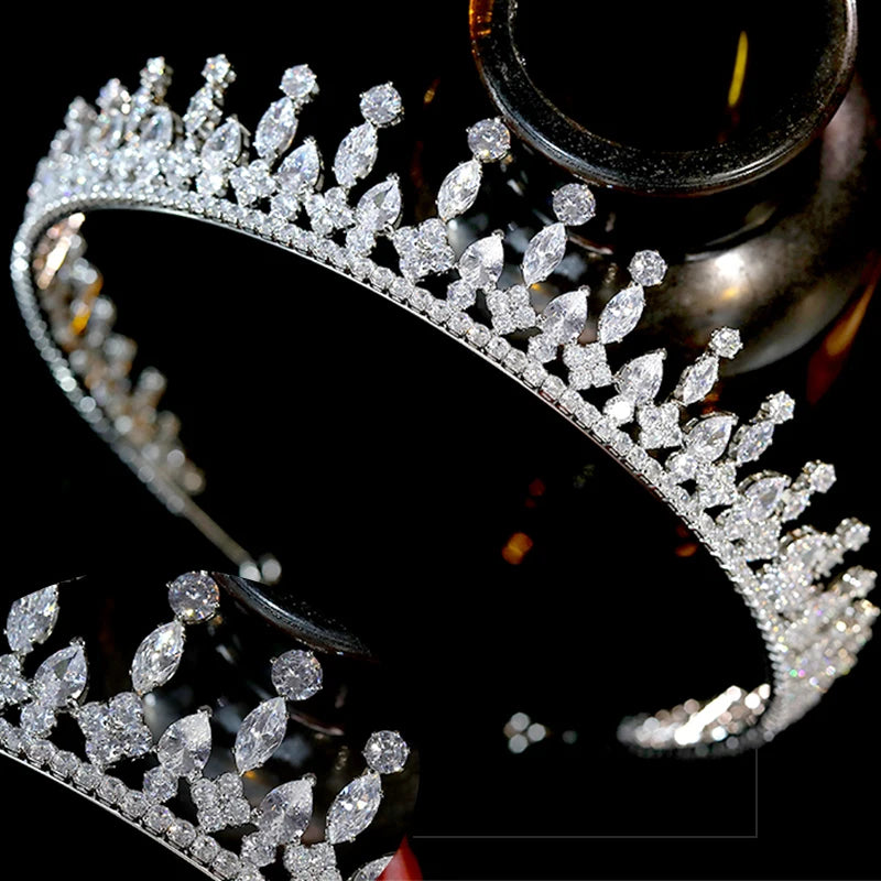 Front profile view of an elegant crystal bridal crown meticulously balanced on a wooden display pedestal.