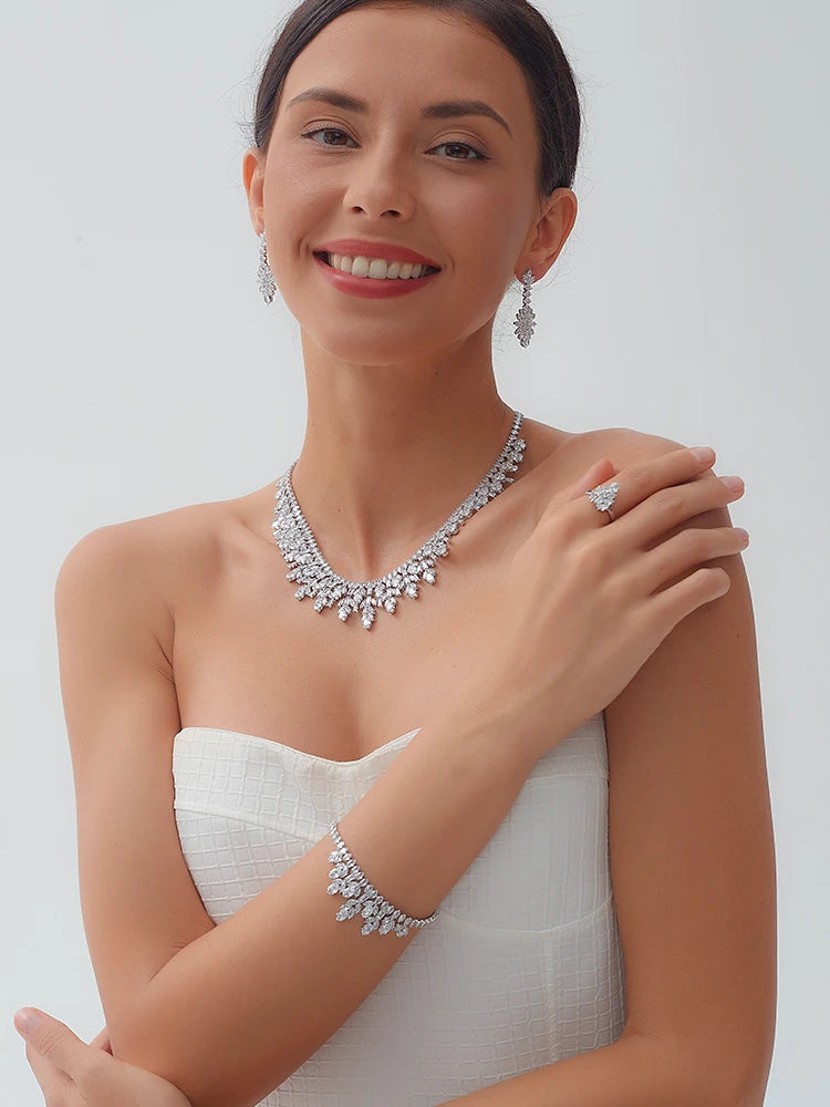 Smiling model wearing an elegant cubic zirconia flower necklace set with matching bridal bracelet, ring, and dangle earrings.