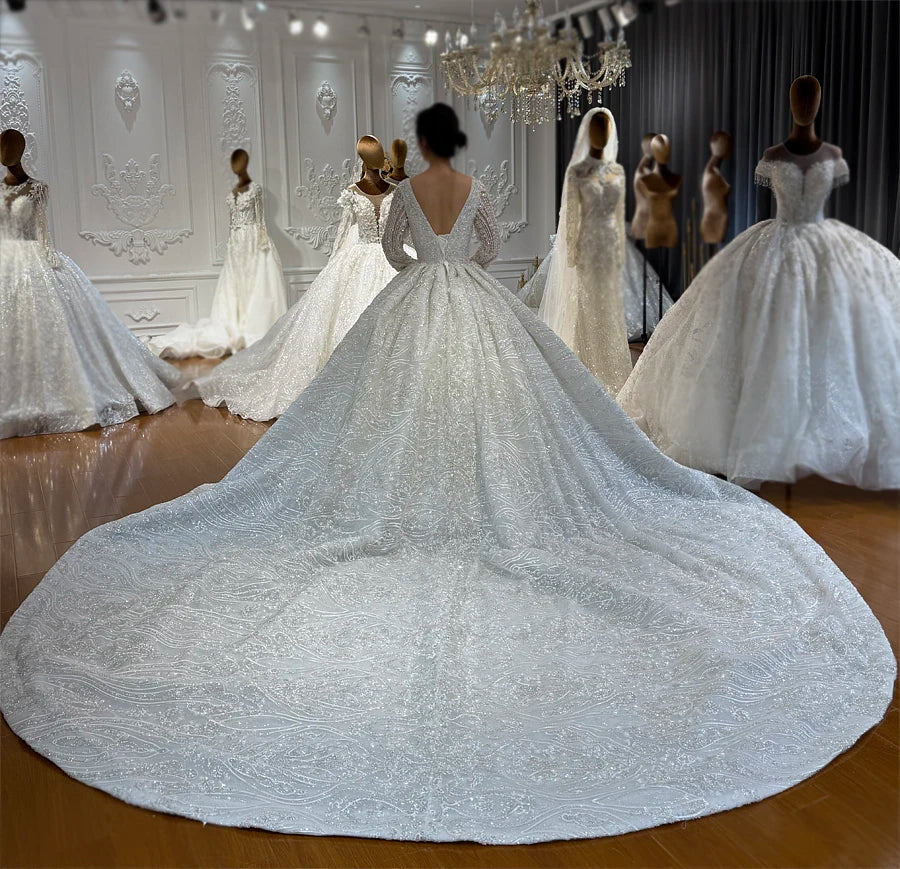 Full back view of an elegant beaded lace ball gown wedding dress with a low V-back and a dramatic, shimmering cathedral-length circular train.