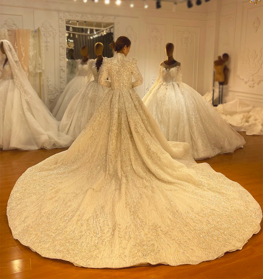 Rear view of a stunning luxury Muslim wedding dress in a showroom, displaying the magnificent scale of the fully beaded, textured cathedral train and elegant silhouette.