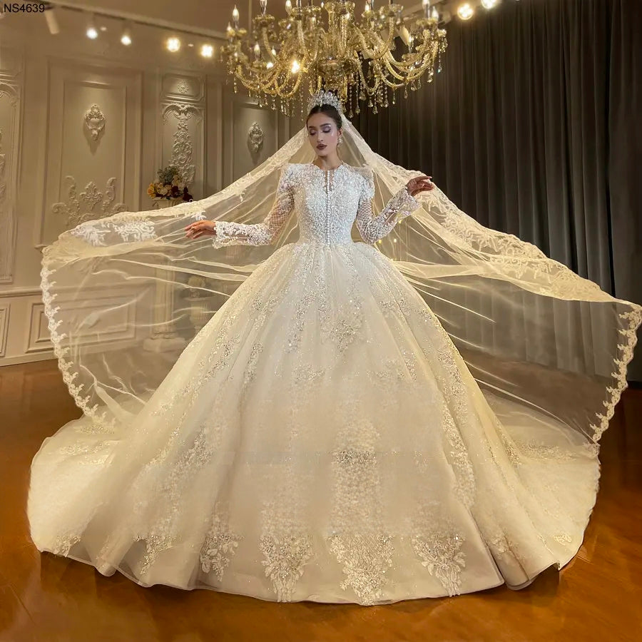 Dramatic front view of a bride wearing an elegant full lace ball gown wedding dress, displaying a wide, sweeping cathedral veil that complements the timeless bridal style.