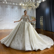 Full-length front view of a model wearing an elegant vintage ball gown wedding dress with a high neckline, long lace sleeves, and a voluminous sparkling skirt.