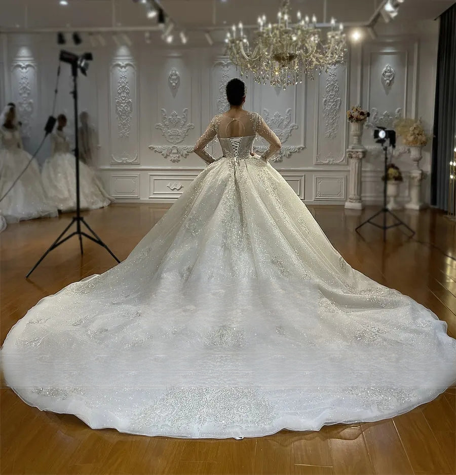 Angled back view of an elegant wedding dress on a mannequin, emphasizing the sophisticated lace-up closure and the flow of the lace-trimmed cathedral train.