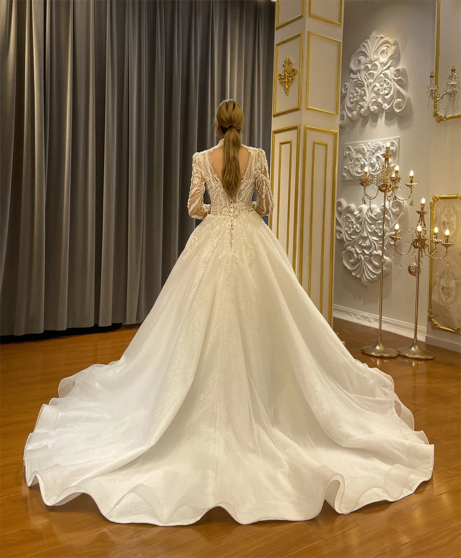 Rear view of an elegant fully beaded A-line wedding dress highlighting the grand sparkly train and regal bridal silhouette.