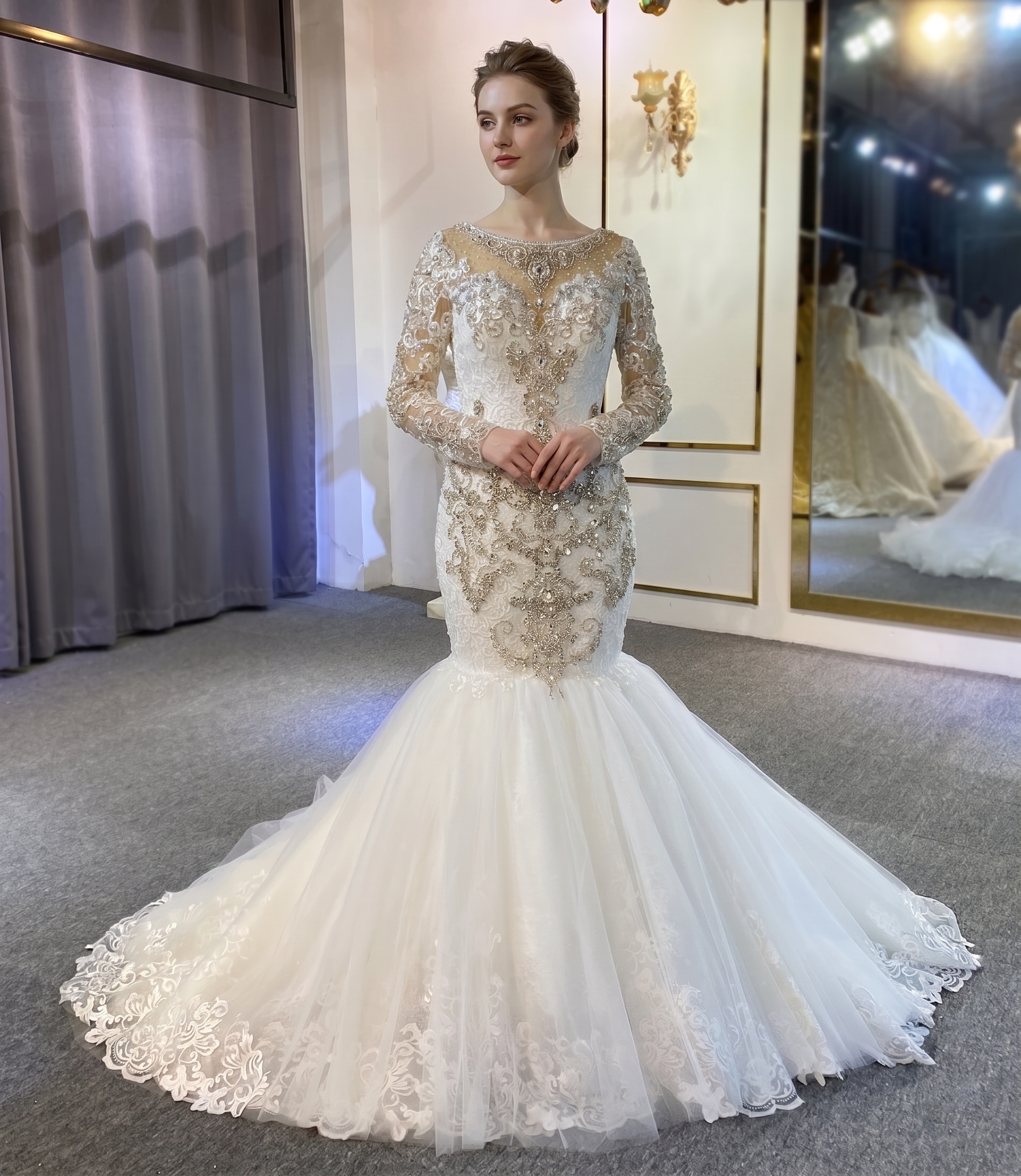 Full-length view of an elegant, heavy beaded mermaid wedding dress featuring sheer long sleeves, intricate silver embroidery, and a voluminous flared tulle skirt on a model.