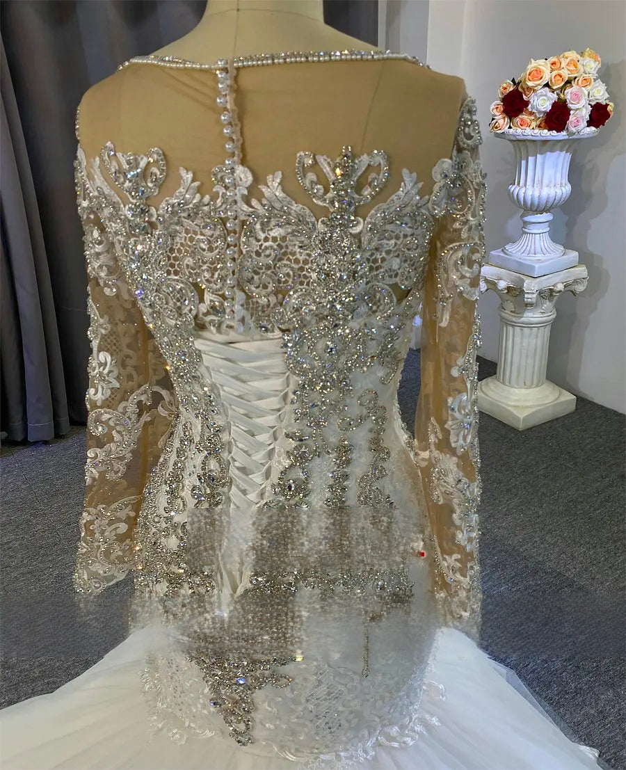 Elegant wedding dress with intricate beading on a mannequin, flowers in the background.