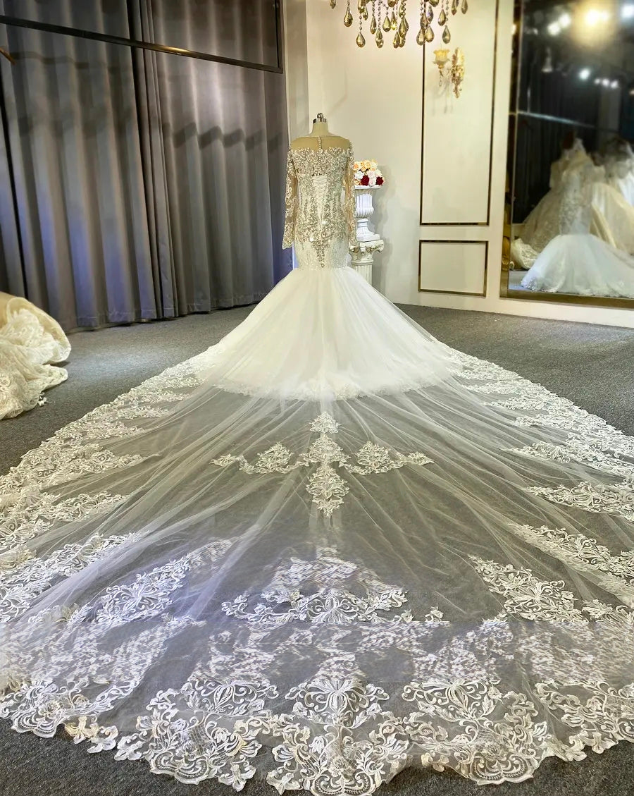 Elegant wedding dress with intricate lace detailing on a mannequin in a room setting.