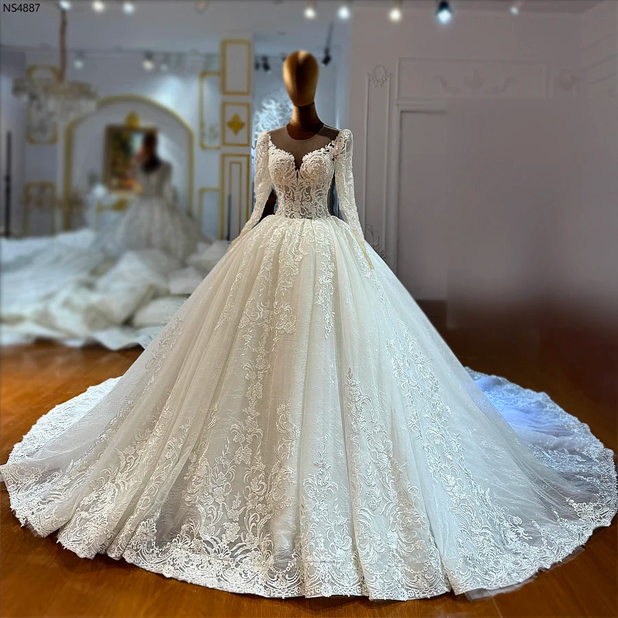 Full-length front view of an elegant lace ball gown wedding dress with long sheer sleeves and a sweetheart illusion neckline.