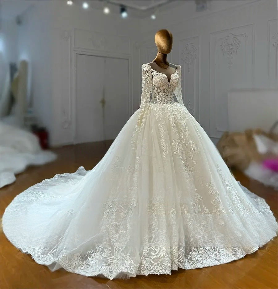 Side profile of a flowing designer wedding dress showcasing a shimmering glitter tulle skirt and a long, embroidered bridal train.