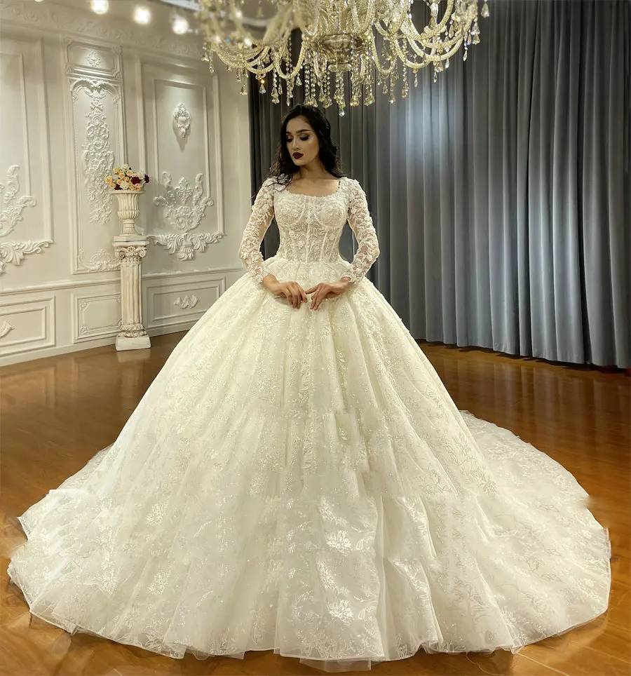 Elegant A-line lace wedding gown with long sleeves, a corset-style bodice, and a voluminous glitter tulle skirt.