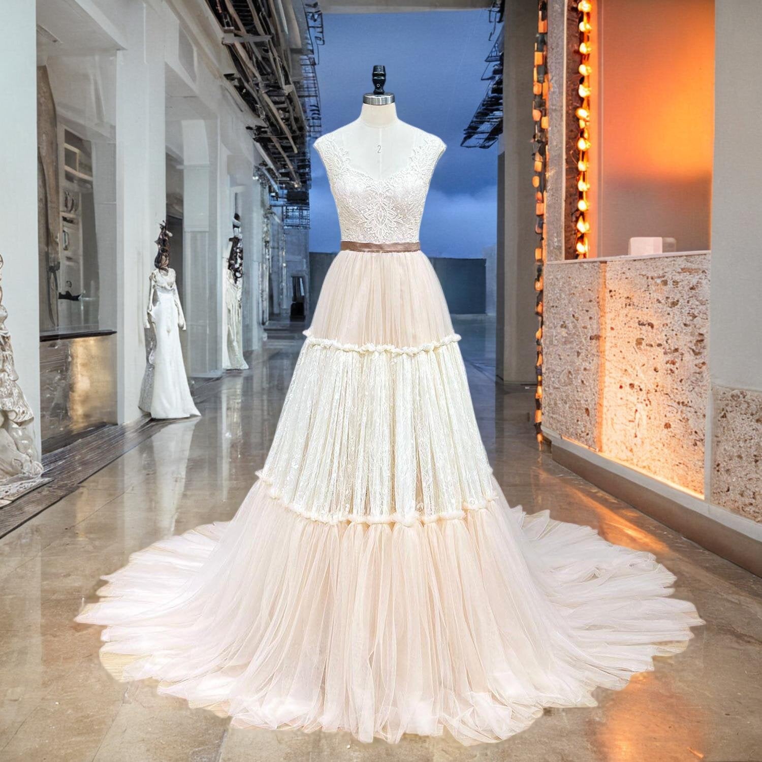 Full view of an elegant layered tulle evening dress with lace bodice on a mannequin inside a boutique showroom.