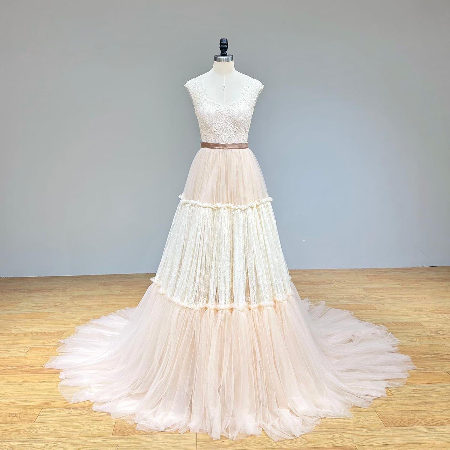 Front view of an elegant sleeveless layered tulle and lace evening gown with a sweetheart neckline on a mannequin.