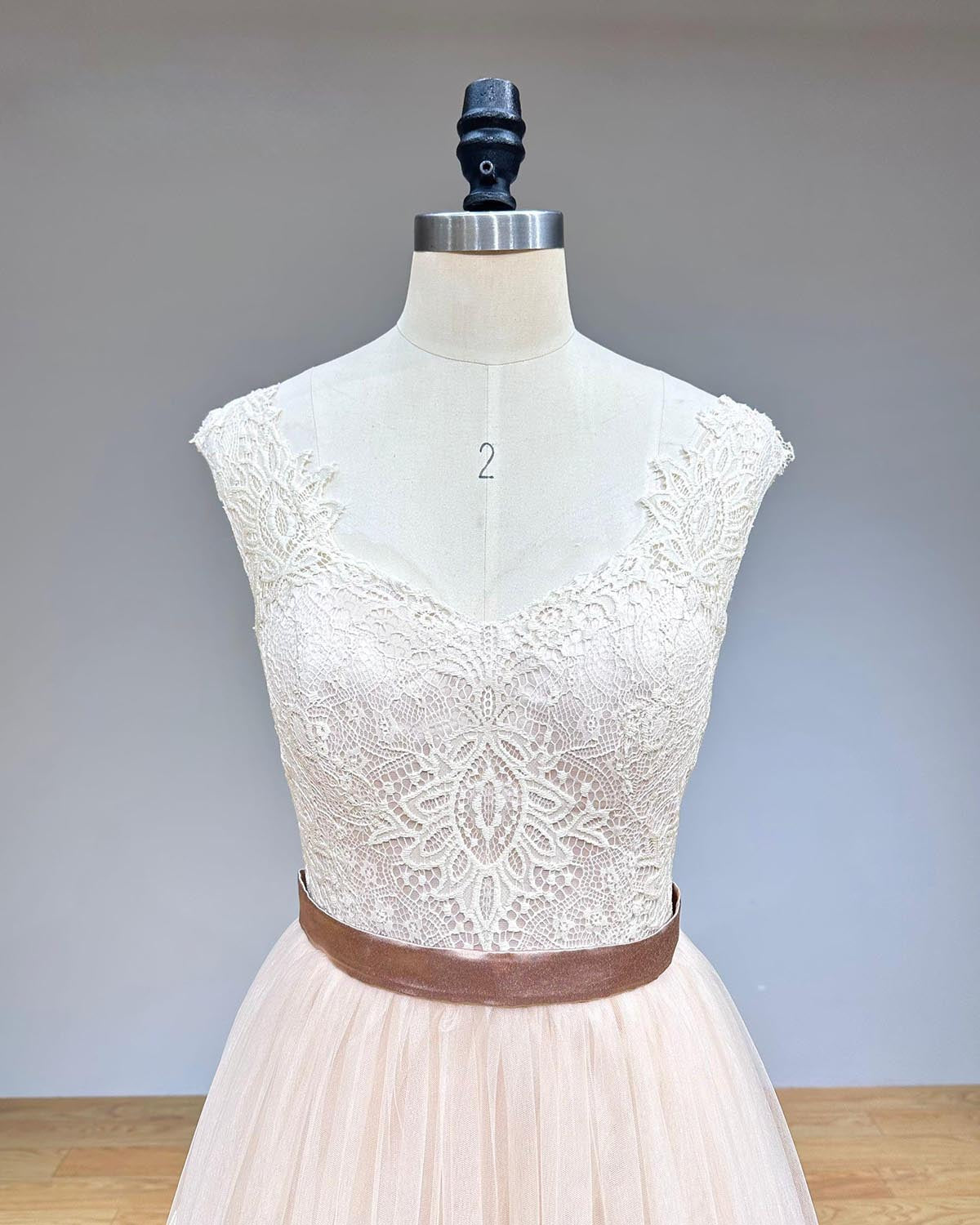 Close-up detail of the intricate lace bodice and sweetheart neckline on an elegant layered tulle evening dress.