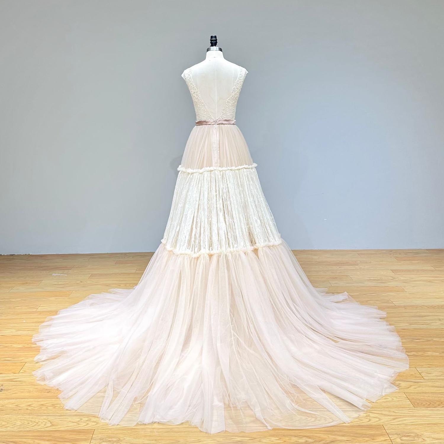 Back view of an elegant V-backless layered tulle and lace evening gown with a train on a mannequin.