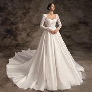 Elegant A-line bridal gown with long lace sleeves, intricate beadwork, and a sweeping court train.
