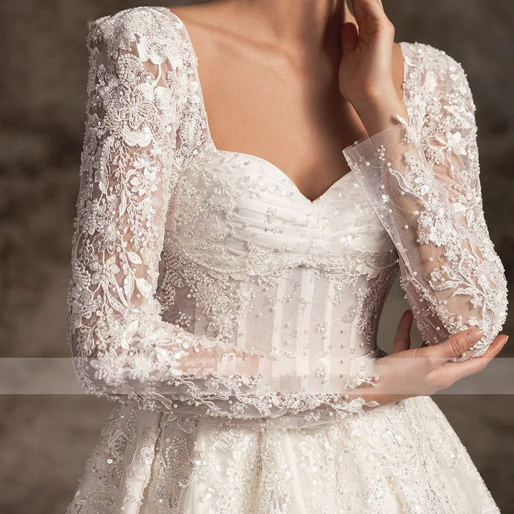 Close-up of the elegant long-sleeve lace bodice on an A-line bridal gown, showcasing intricate beadwork and a sweetheart neckline.