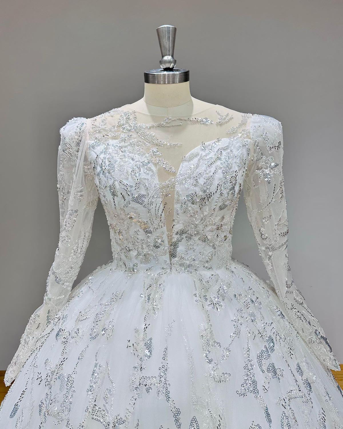 Detailed close-up of the illusion back and delicate button closure on an elegant long-sleeve lace wedding ball gown.