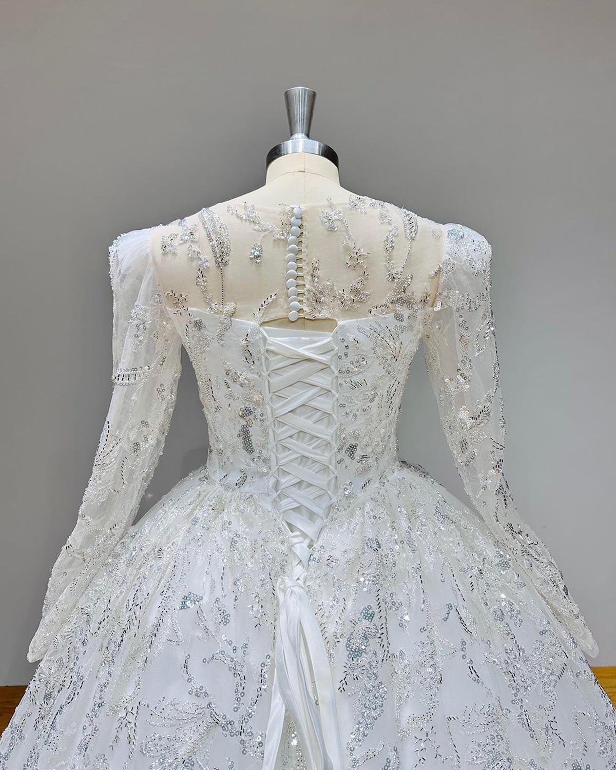 Detailed back close-up of the illusion back and delicate button closure on an elegant long-sleeve lace wedding ball gown.
