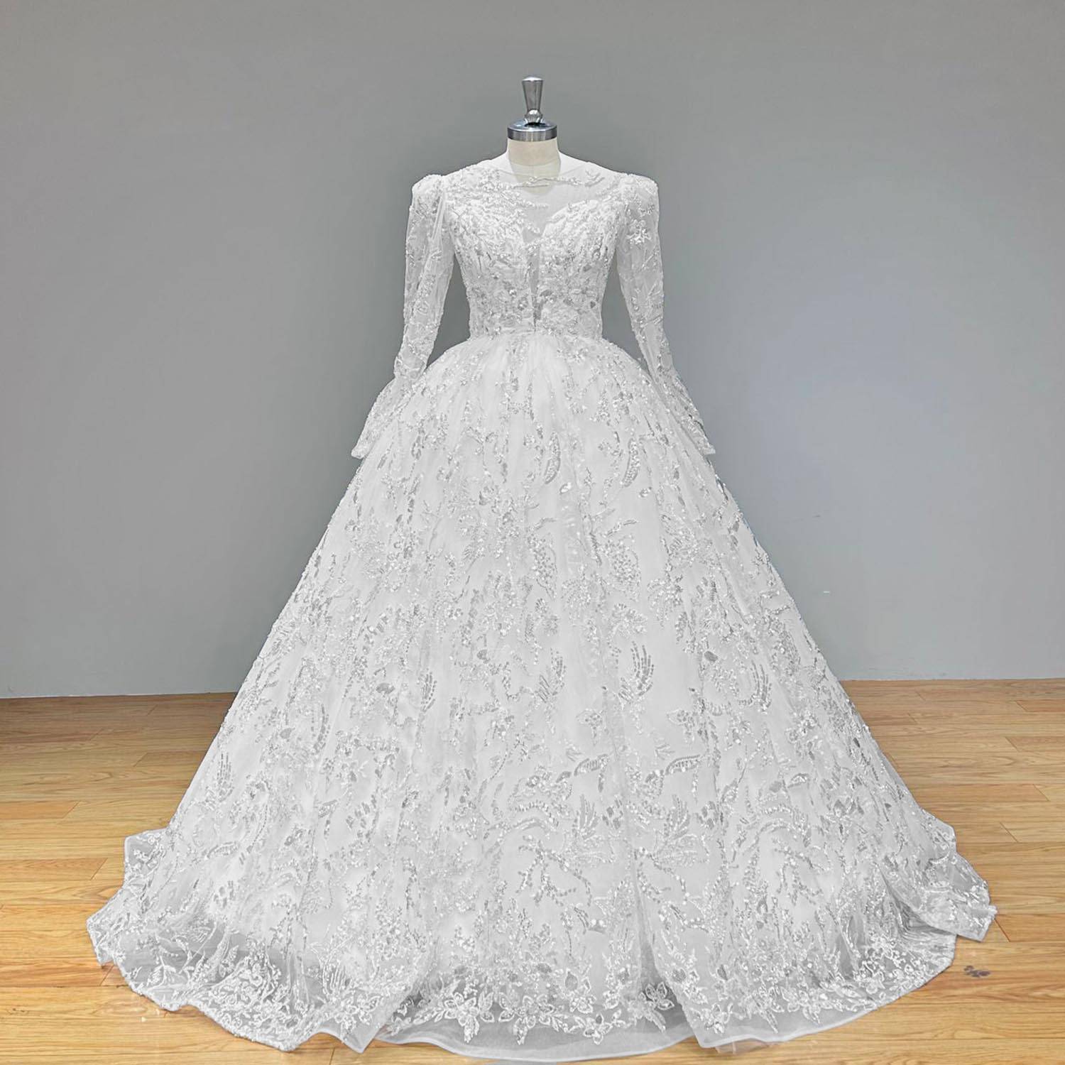 Elegant long-sleeve ball gown wedding dress with illusion back and intricate lace detailing shown from a rear perspective on a mannequin.