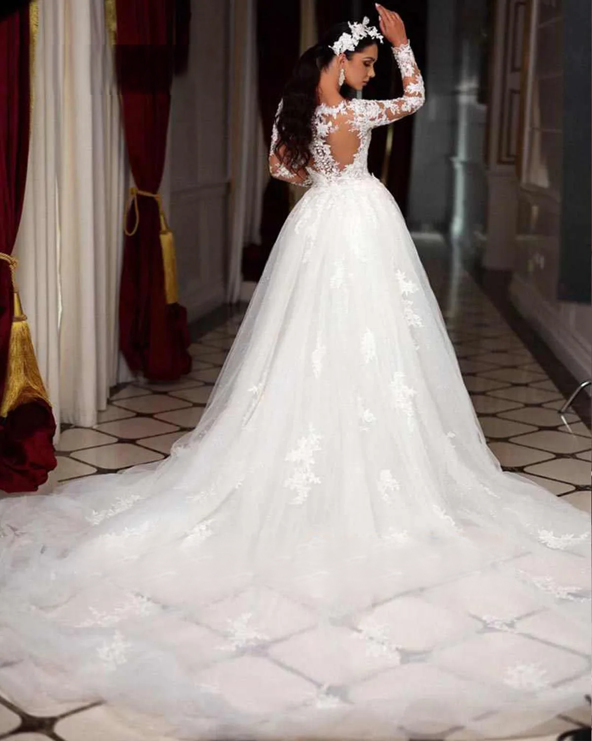 Rear view of a stunning bride in an elegant long sleeve mermaid wedding dress, showing off the illusion lace back and the dramatic spread of the detachable train.