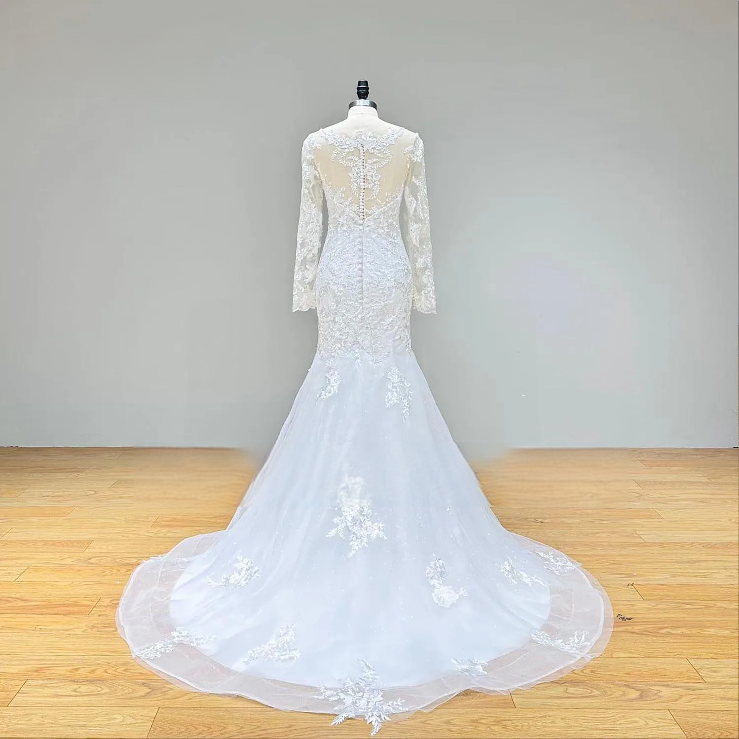 Back view of the fitted long sleeve mermaid wedding dress without the overskirt, highlighting the sheer lace back design and the elegant chapel-length train.