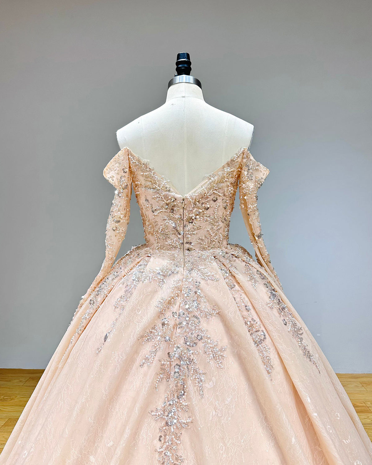 Wide front studio view of a timeless long sleeve wedding dress on a mannequin, emphasizing the detailed beaded lace embroidery and the elegant, flowing skirt.