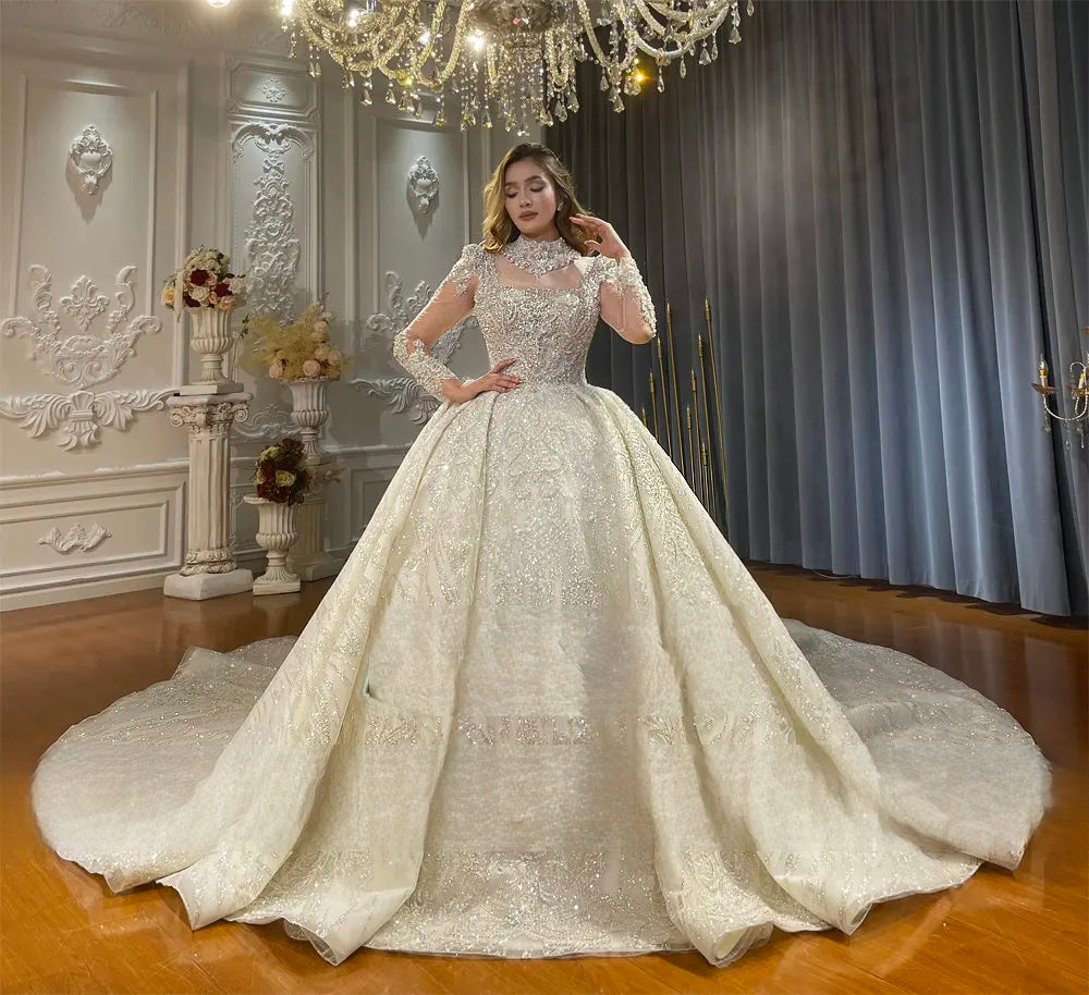 Full-length front perspective of a modern luxury ball gown wedding dress showcasing the voluminous flared skirt and intricate silver sequin detailing under a chandelier.