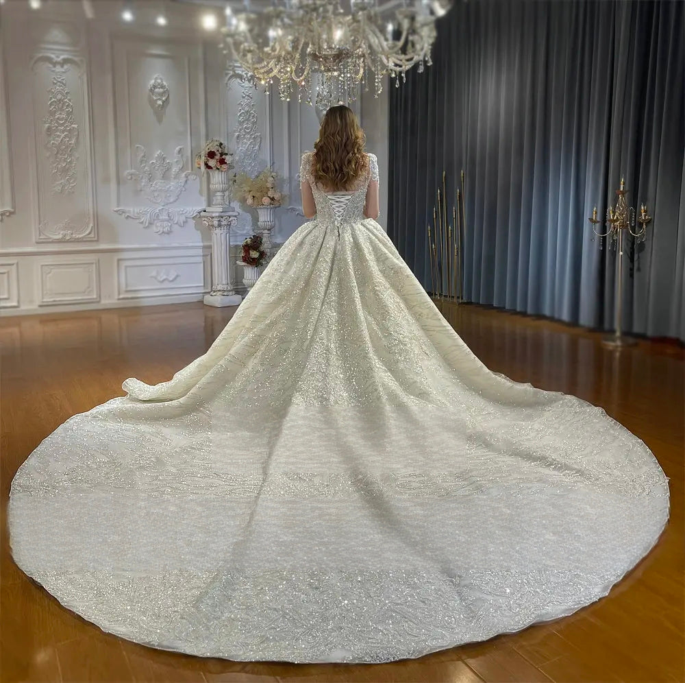 Rear view of the luxury bridal gown displaying a wide, circular cathedral-length train and a traditional corset lace-up back design.