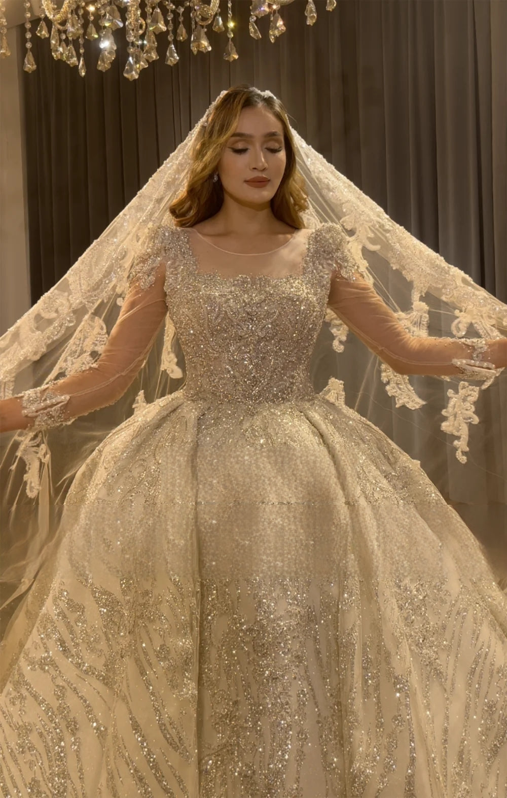 Detailed front view of a bride wearing a luxury wedding dress with a shimmering bodice and a lace-trimmed bridal veil, highlighting the modern silhouette.