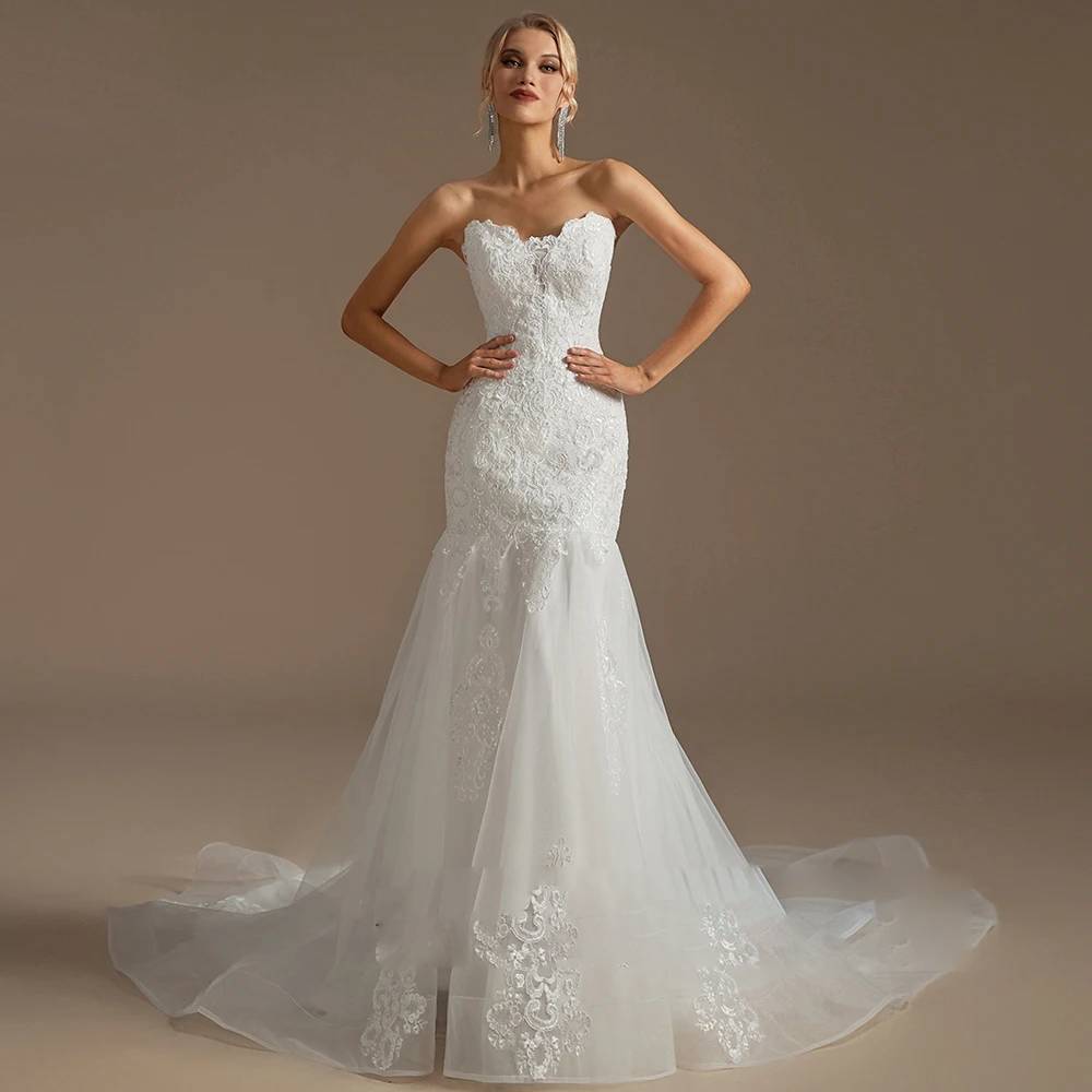 Full-length studio portrait of a glamorous strapless bridal gown with a structured lace bodice and a flared tulle mermaid skirt.