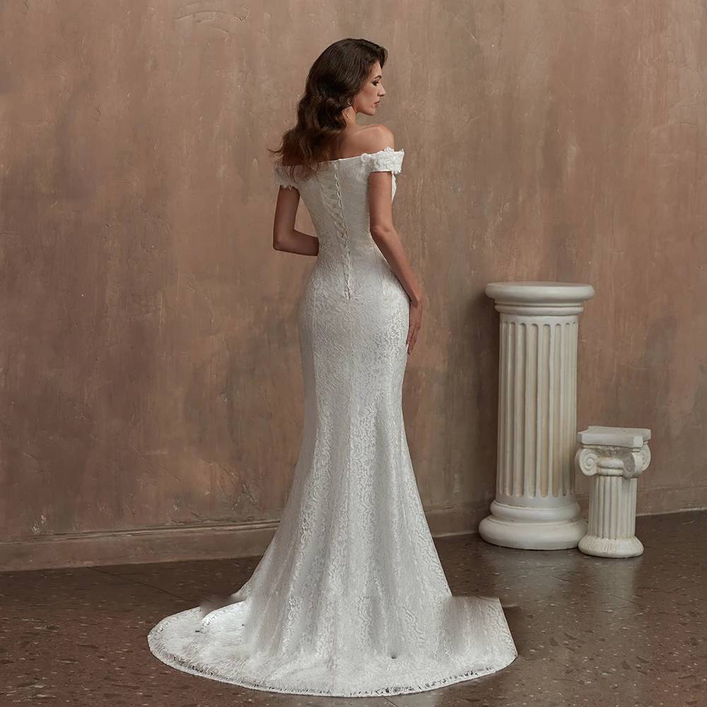 Back view of a form-fitting lace bridal gown highlighting an intricate lace-up corset back detail and a romantic sweeping train.
