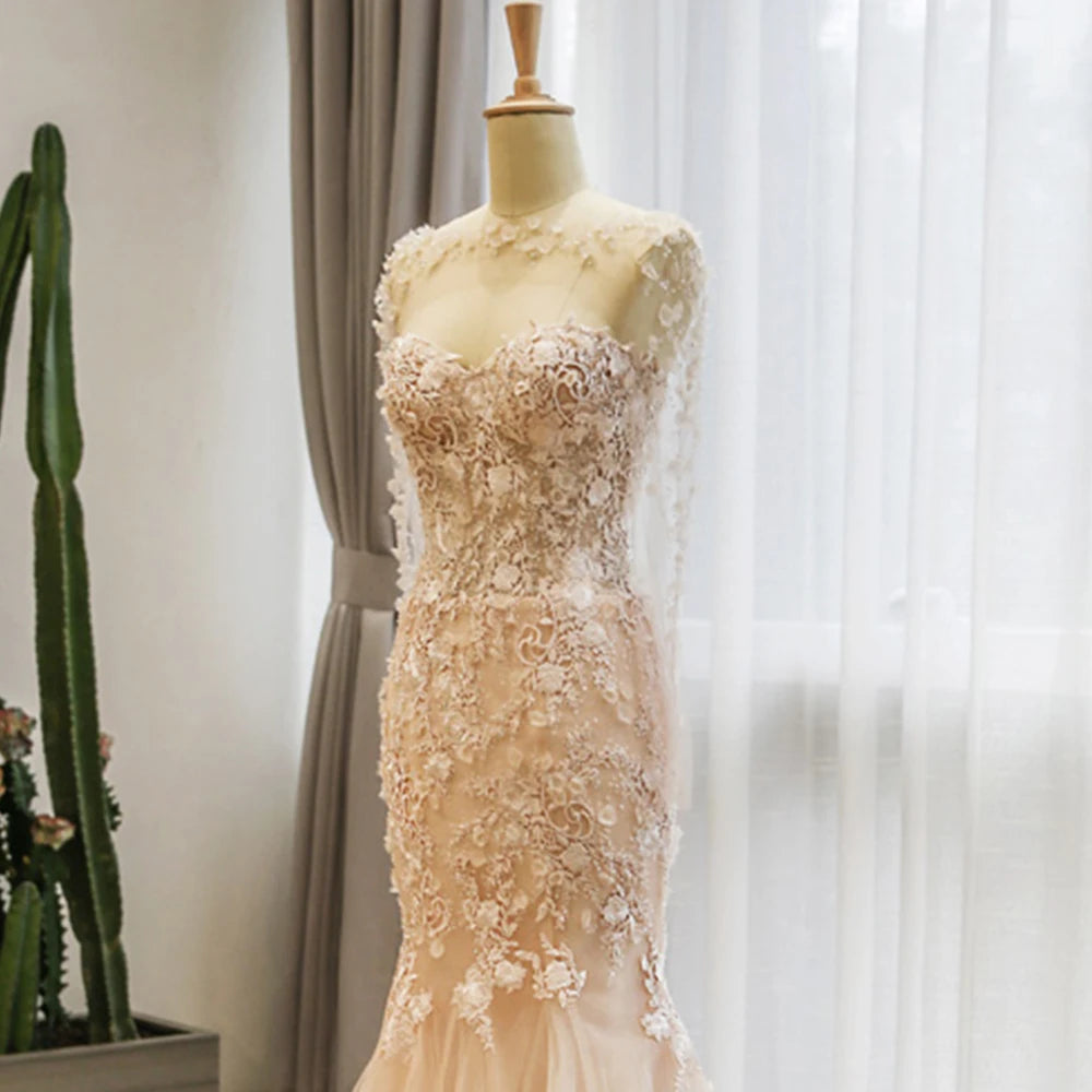 Champagne lace-up mermaid wedding dress on a dress form, highlighting the sheer illusion overlay with delicate beaded floral appliques and a matching matching bridal shawl extension.