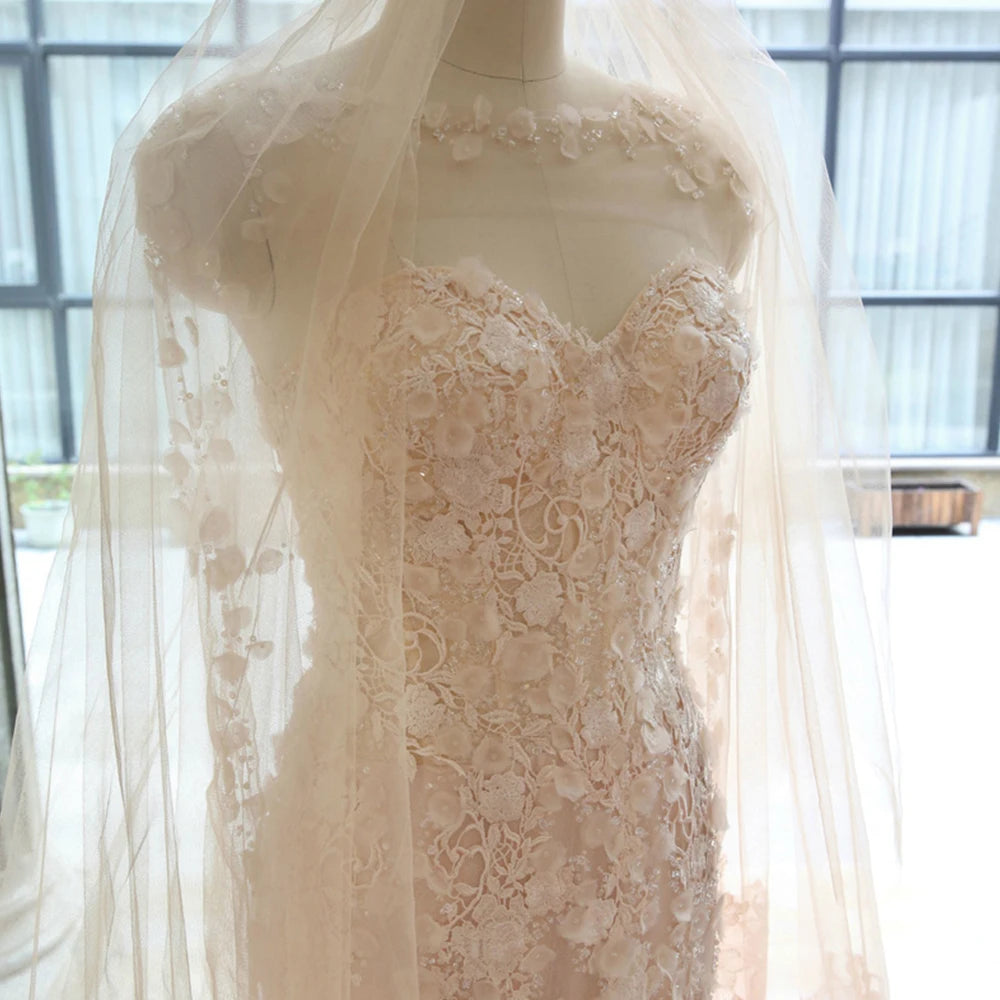 Detailed close-up of a sweetheart bridal gown corset on a mannequin, covered in 3D flower appliques and intricately draped under a matching sheer tulle wedding veil.